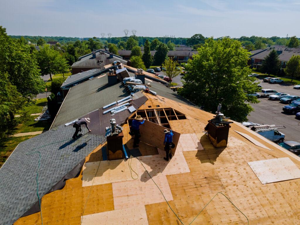 Roofer at work on a residential home in North Carolina, laying shingles and using professional tools, with the beautiful North Carolina landscape in the background.