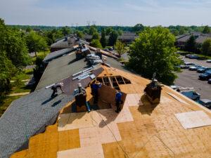 Roofer at work on a residential home in North Carolina, laying shingles and using professional tools, with the beautiful North Carolina landscape in the background.