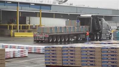 Flatbed truck carrying a load of roofing shingles, representing rising roofing material costs